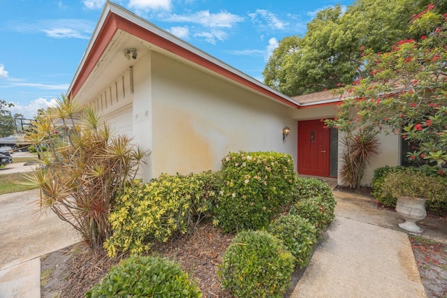 doorway to property featuring stucco siding and an attached garage