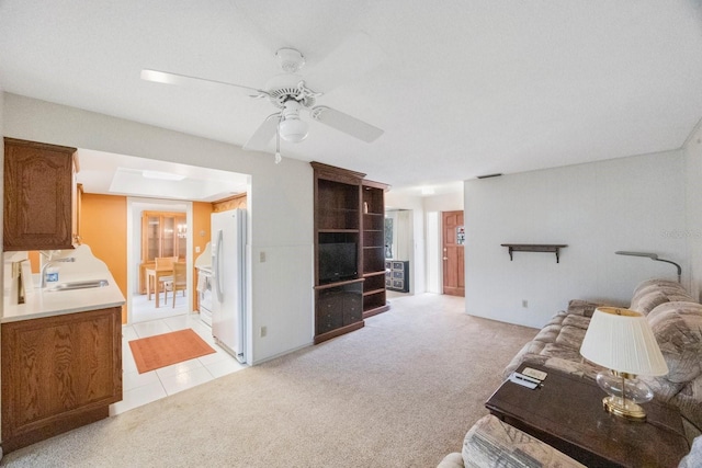 living area with a ceiling fan and light carpet