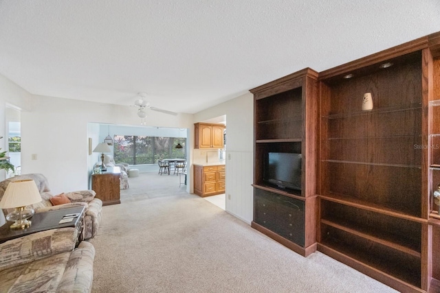 living area featuring light colored carpet, ceiling fan, and vaulted ceiling