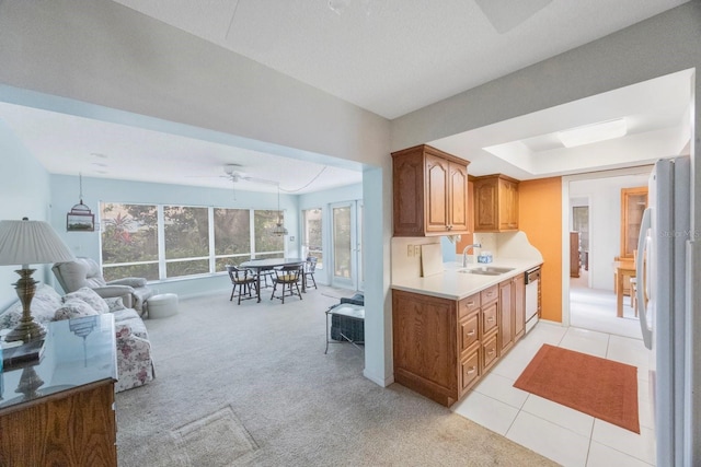 kitchen featuring freestanding refrigerator, dishwashing machine, a sink, light countertops, and ceiling fan