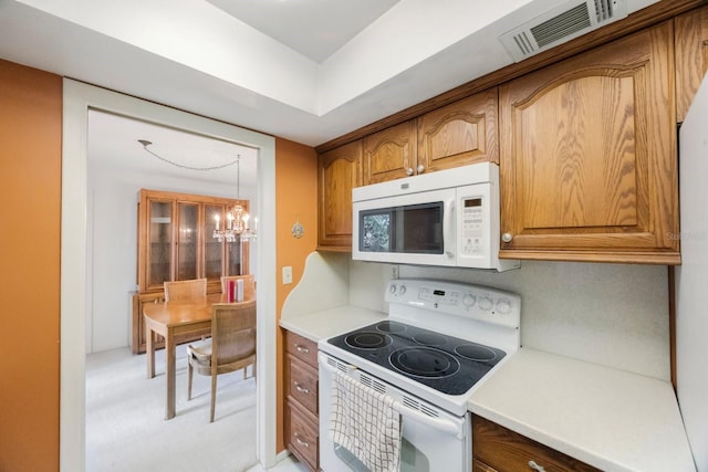 kitchen featuring white appliances, brown cabinets, a chandelier, light countertops, and light colored carpet