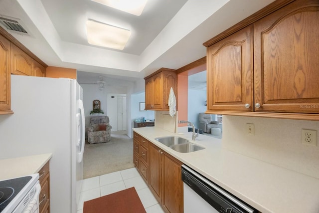 kitchen featuring a sink, white appliances, light colored carpet, brown cabinetry, and light countertops