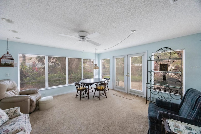 sunroom / solarium with a ceiling fan, carpet, french doors, and a textured ceiling