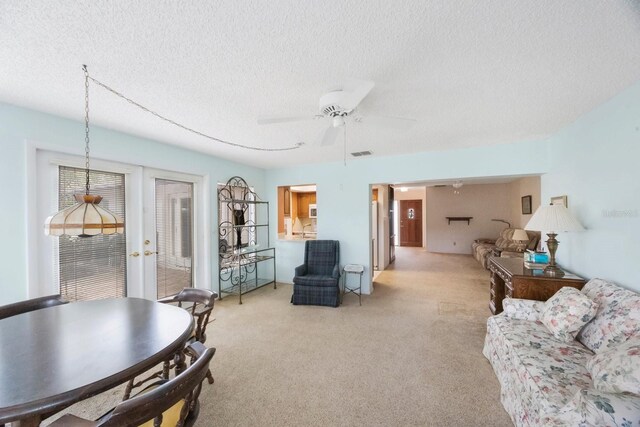 living room with a textured ceiling, light colored carpet, french doors, and a ceiling fan