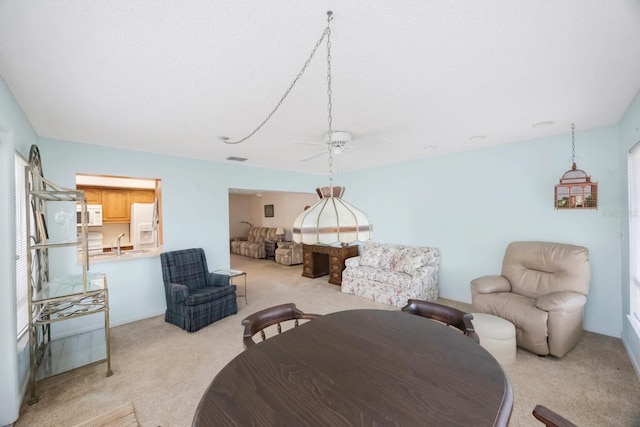 dining space with light colored carpet and ceiling fan