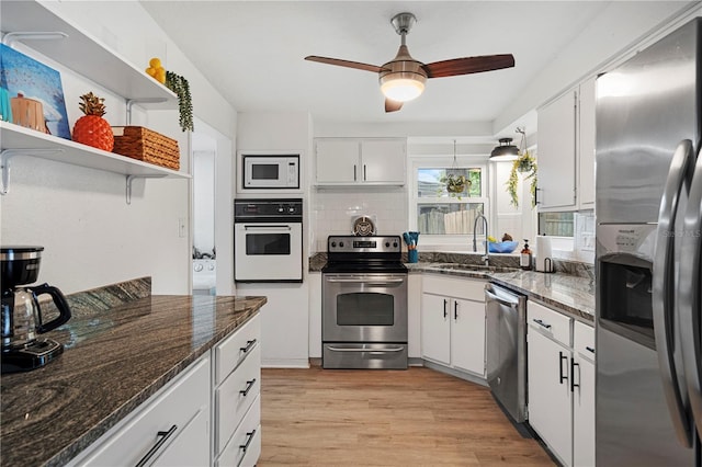 kitchen featuring stainless steel appliances, a sink, white cabinetry, light wood-style floors, and a ceiling fan