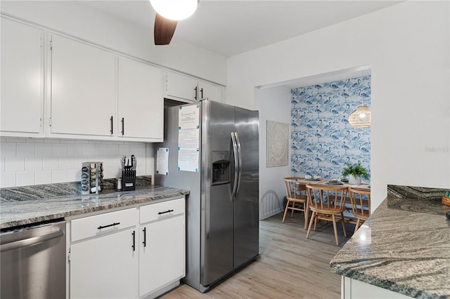 kitchen with appliances with stainless steel finishes, white cabinets, decorative backsplash, and light wood-style flooring