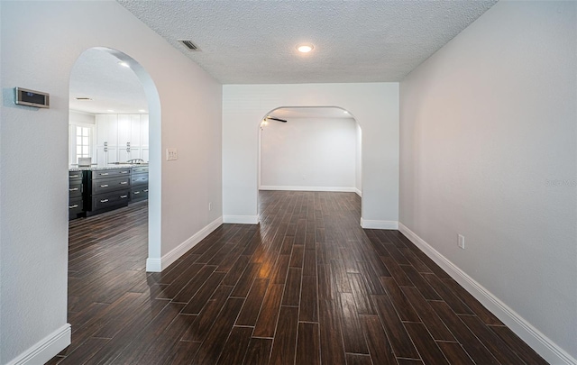 1402 Oleander Dr, Tarpon Springs, FL 34689 - hall featuring dark wood-style floors, arched walkways, baseboards, and a textured ceiling