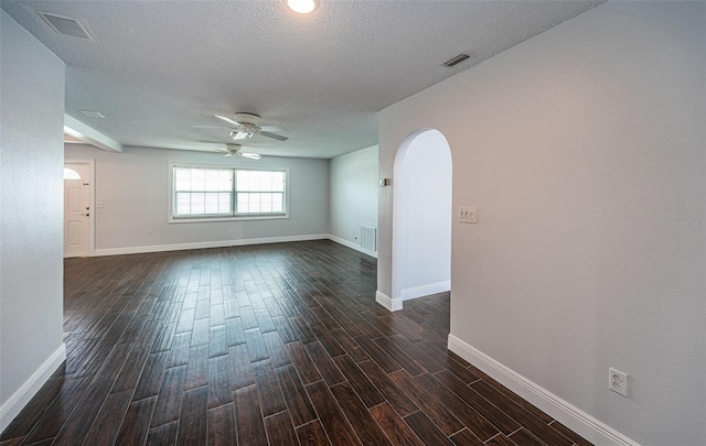 1402 Oleander Dr, Tarpon Springs, FL 34689 - empty room with a ceiling fan, arched walkways, baseboards, dark wood finished floors, and a textured ceiling