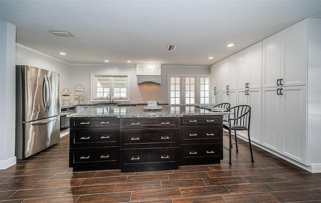 1402 Oleander Dr, Tarpon Springs, FL 34689 - kitchen featuring stainless steel appliances, white cabinetry, wood finish floors, ornamental molding, and dark cabinets