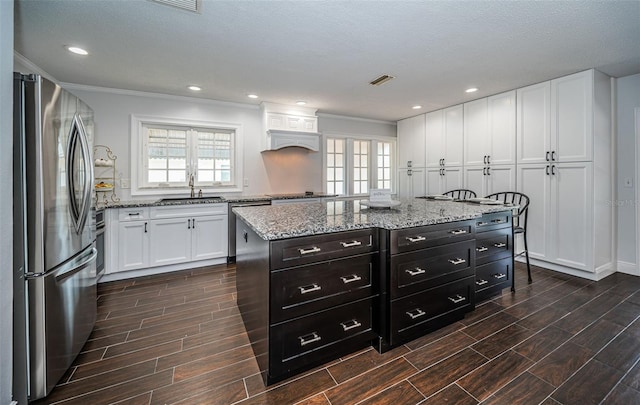 1402 Oleander Dr, Tarpon Springs, FL 34689 - kitchen featuring stainless steel appliances, a sink, white cabinets, wood finish floors, and dark cabinetry