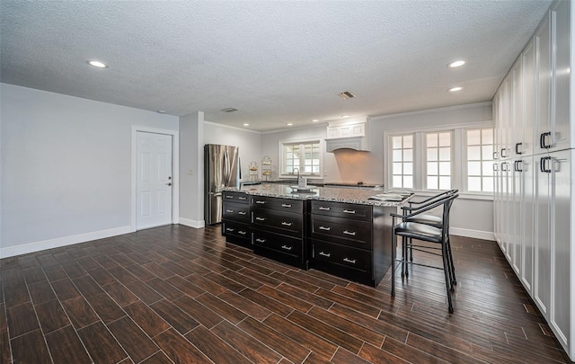 1402 Oleander Dr, Tarpon Springs, FL 34689 - kitchen with freestanding refrigerator, dark cabinets, baseboards, a textured ceiling, and a center island