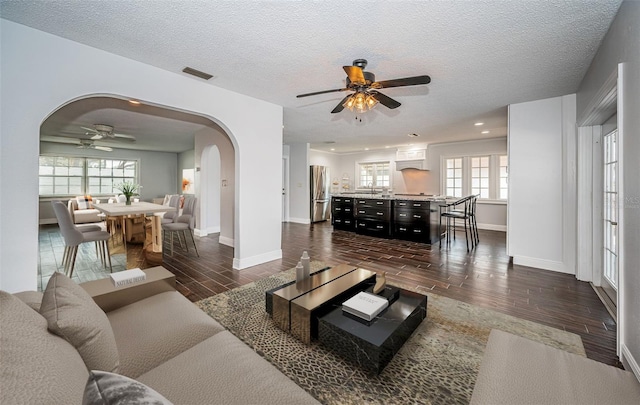 1402 Oleander Dr, Tarpon Springs, FL 34689 - living room with a ceiling fan, dark wood finished floors, arched walkways, baseboards, and a textured ceiling