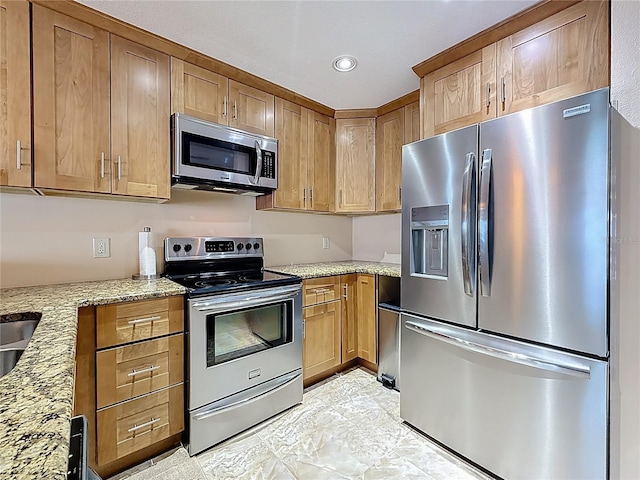 230 Medallion Blvd Unit G, Madeira Beach, FL 33708 - kitchen with stainless steel appliances, light stone countertops, recessed lighting, and brown cabinetry