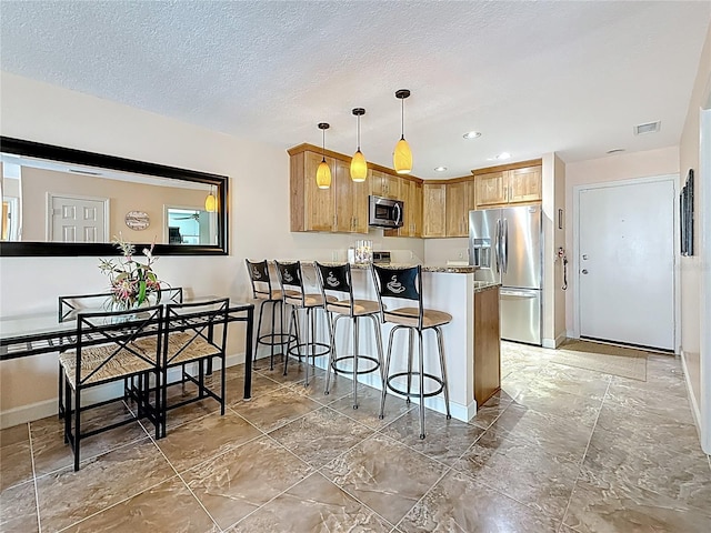 230 Medallion Blvd Unit G, Madeira Beach, FL 33708 - kitchen featuring appliances with stainless steel finishes, baseboards, a peninsula, a kitchen bar, and recessed lighting