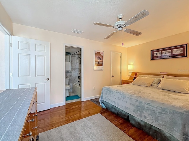 230 Medallion Blvd Unit G, Madeira Beach, FL 33708 - bedroom featuring dark wood-style flooring, baseboards, connected bathroom, and ceiling fan