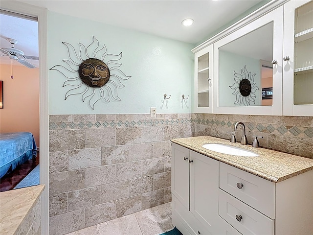230 Medallion Blvd Unit G, Madeira Beach, FL 33708 - bathroom featuring a ceiling fan, tile walls, vanity, and a wainscoted wall
