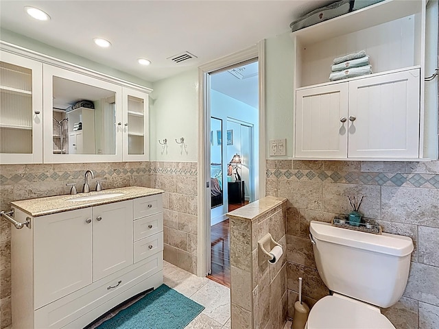 230 Medallion Blvd Unit G, Madeira Beach, FL 33708 - bathroom featuring tile walls, toilet, vanity, tile patterned floors, and wainscoting