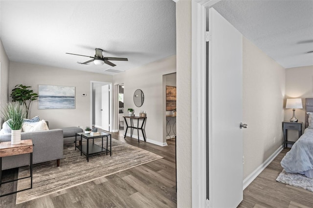 living room with wood finished floors, ceiling fan, a textured ceiling, and baseboards