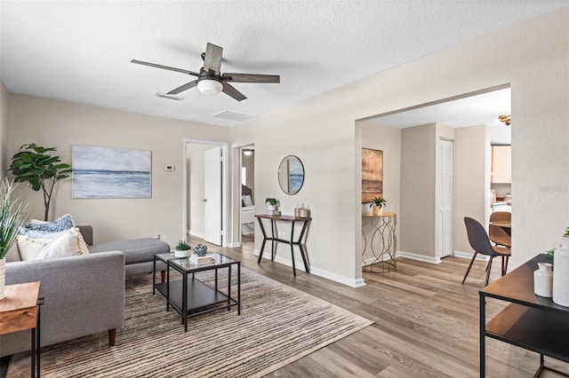 living room with wood finished floors, baseboards, and a ceiling fan