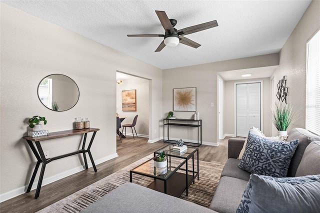 living area with wood finished floors, a ceiling fan, and baseboards