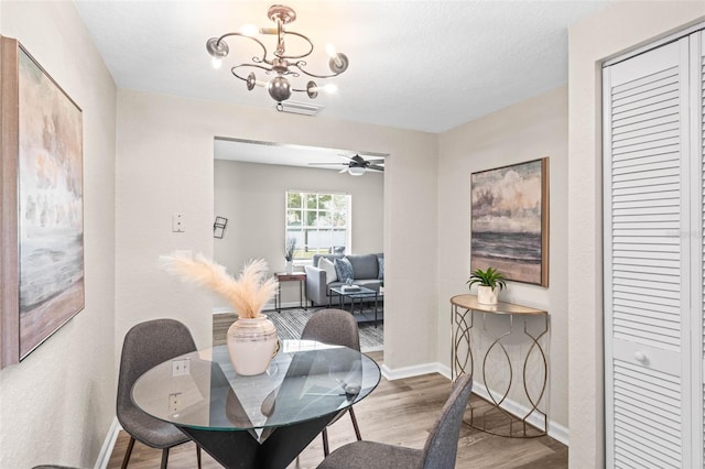 dining area with wood finished floors, a chandelier, ceiling fan, and baseboards