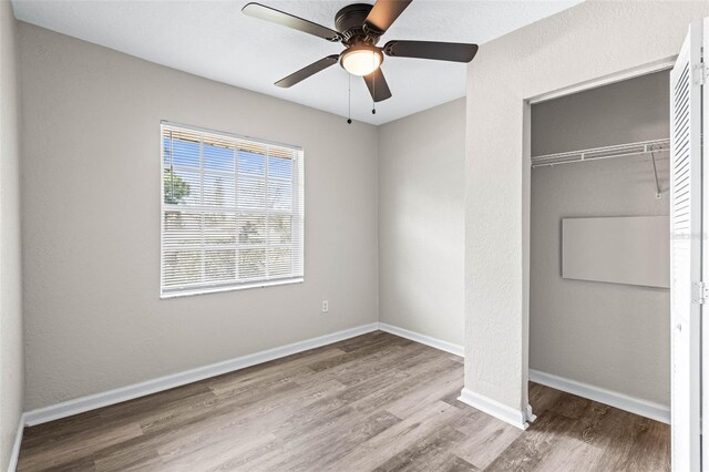 unfurnished bedroom with a closet, wood finished floors, baseboards, and a ceiling fan