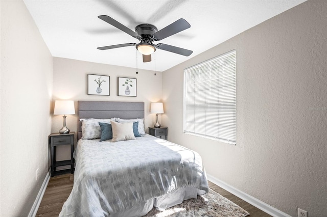 bedroom featuring wood finished floors, baseboards, a textured wall, and a ceiling fan