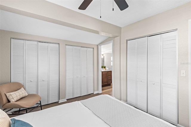 bedroom featuring multiple closets, lofted ceiling, ceiling fan, and baseboards