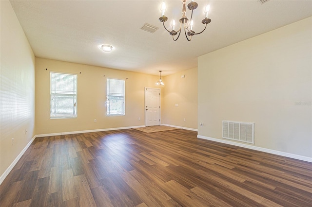 unfurnished room with a chandelier, dark wood-type flooring, and baseboards