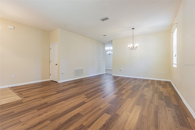 unfurnished room featuring a chandelier, wood finished floors, and baseboards