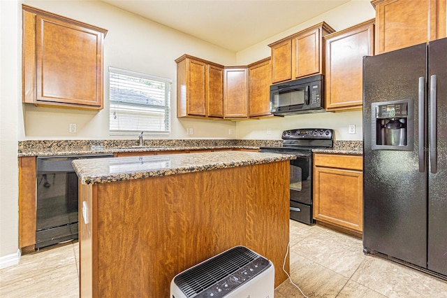 kitchen with black appliances, dark stone countertops, a kitchen island, a sink, and brown cabinetry