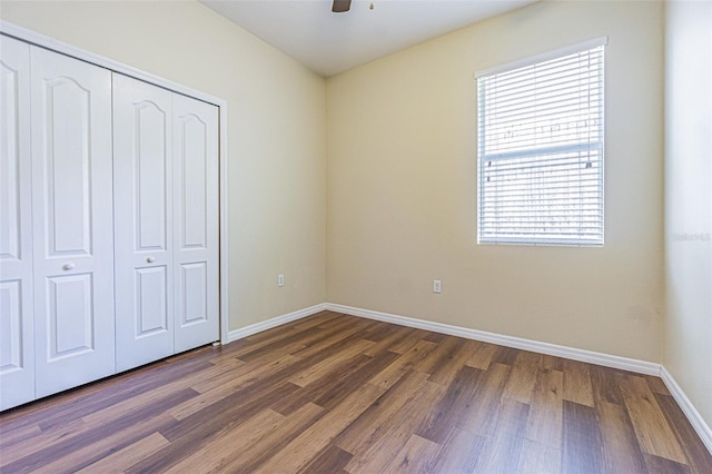 unfurnished bedroom with wood finished floors, baseboards, a closet, and a ceiling fan