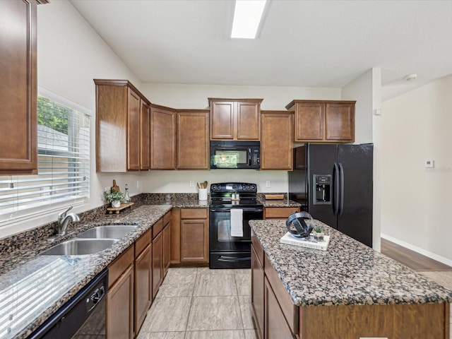 12212 Mcmullen Loop, Riverview, FL 33569 - kitchen with black appliances, a sink, dark stone countertops, a kitchen island, and brown cabinetry
