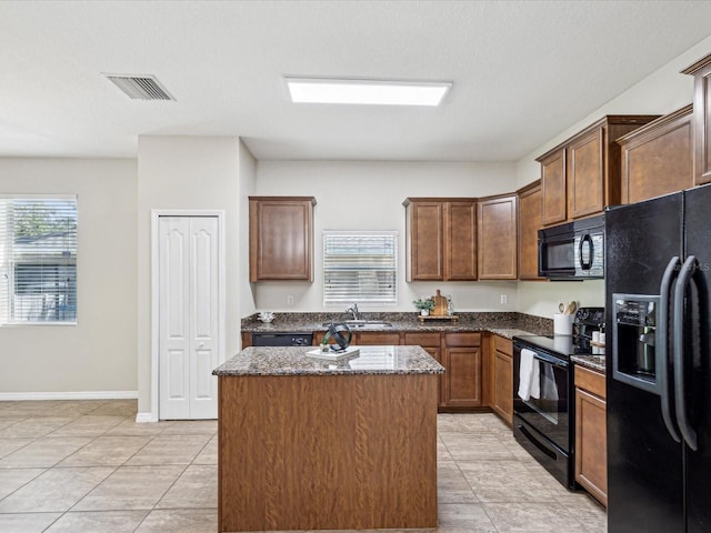 12212 Mcmullen Loop, Riverview, FL 33569 - kitchen featuring black appliances, a center island, a sink, dark stone counters, and baseboards
