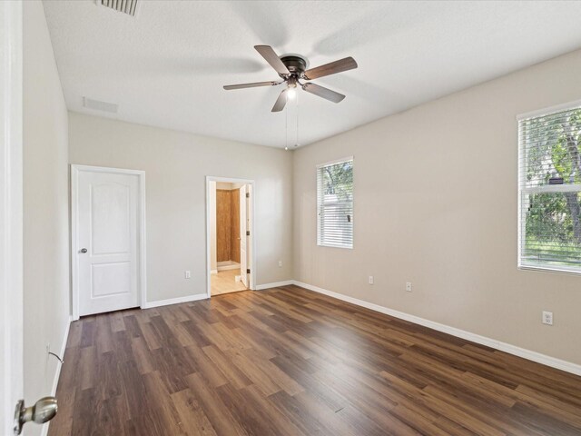 12212 Mcmullen Loop, Riverview, FL 33569 - unfurnished bedroom featuring dark wood-style floors, baseboards, ensuite bathroom, and ceiling fan