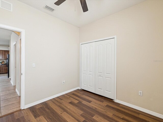 12212 Mcmullen Loop, Riverview, FL 33569 - unfurnished bedroom featuring dark wood-style floors, freestanding refrigerator, and baseboards