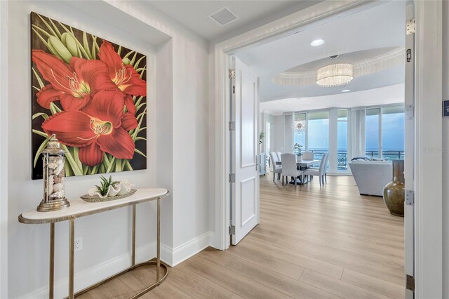 140 Riviera Dunes Way Unit 1203, Palmetto, FL 34221 - hall featuring wood finished floors, a chandelier, baseboards, and a tray ceiling