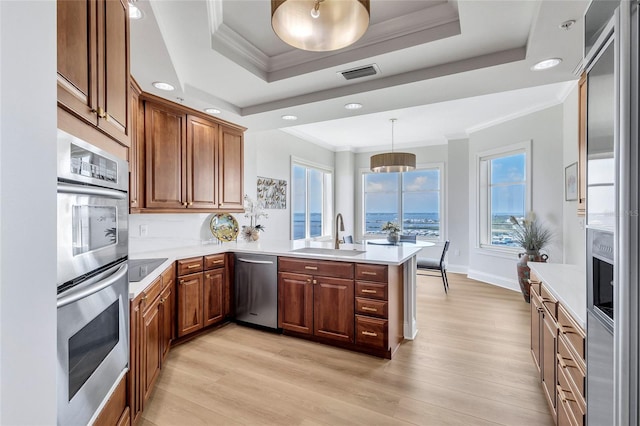140 Riviera Dunes Way Unit 1203, Palmetto, FL 34221 - kitchen featuring a sink, stainless steel appliances, a peninsula, a raised ceiling, and light wood-style flooring