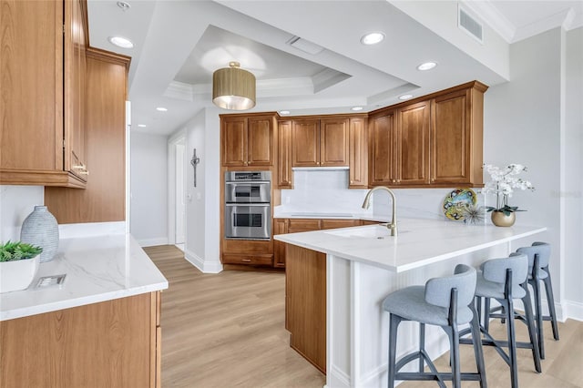 140 Riviera Dunes Way Unit 1203, Palmetto, FL 34221 - kitchen featuring ornamental molding, a peninsula, light wood-type flooring, baseboards, and stainless steel double oven