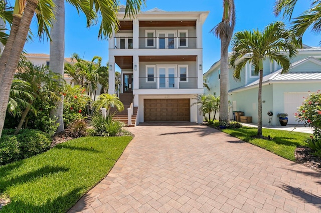 443 18th Ave, Indian Rocks Beach, FL 33785 - view of front facade featuring a balcony, decorative driveway, stairway, a garage, and a front lawn