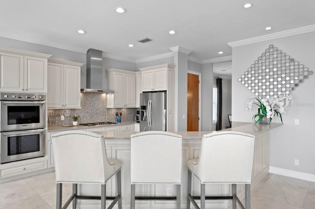 443 18th Ave, Indian Rocks Beach, FL 33785 - kitchen featuring stainless steel appliances, wall chimney exhaust hood, a breakfast bar, light countertops, and tasteful backsplash