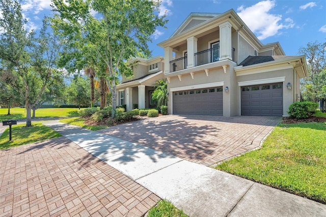 5117 Longspur Ct, Lithia, FL 33547 - neoclassical / greek revival house with stucco siding, decorative driveway, a balcony, a front yard, and a garage