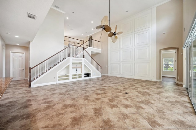 5117 Longspur Ct, Lithia, FL 33547 - unfurnished living room featuring stairway, a towering ceiling, a ceiling fan, arched walkways, and baseboards
