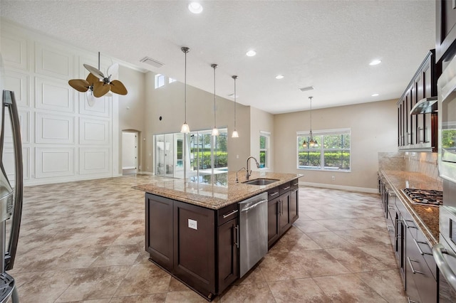 5117 Longspur Ct, Lithia, FL 33547 - kitchen with appliances with stainless steel finishes, a sink, dark brown cabinetry, baseboards, and light stone countertops