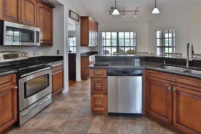 kitchen with appliances with stainless steel finishes, a sink, decorative light fixtures, and brown cabinetry