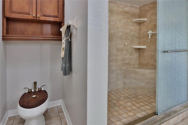 bathroom featuring tiled shower, tile patterned flooring, and baseboards