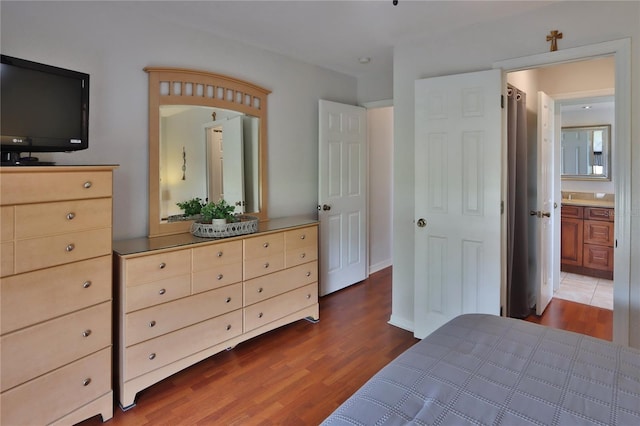 bedroom featuring wood finished floors and ensuite bathroom