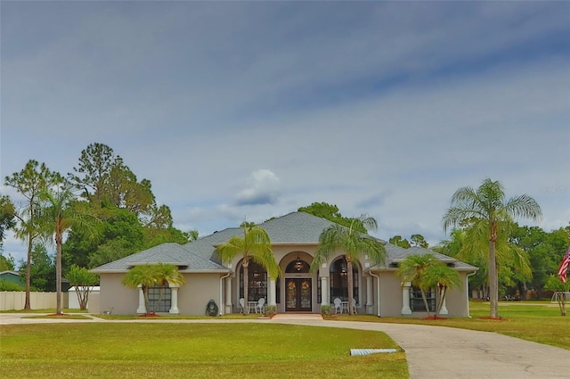 mediterranean / spanish-style house with french doors, curved driveway, and stucco siding