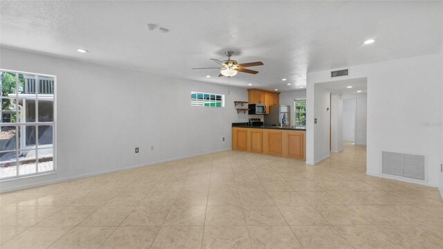 9050 Lake Place Ln, Tampa, FL 33634 - kitchen with stainless steel microwave, plenty of natural light, recessed lighting, ceiling fan, and dark countertops